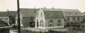 Achter de paal de kosterswoning en daarachter het gebouw van Christelijke Belangen